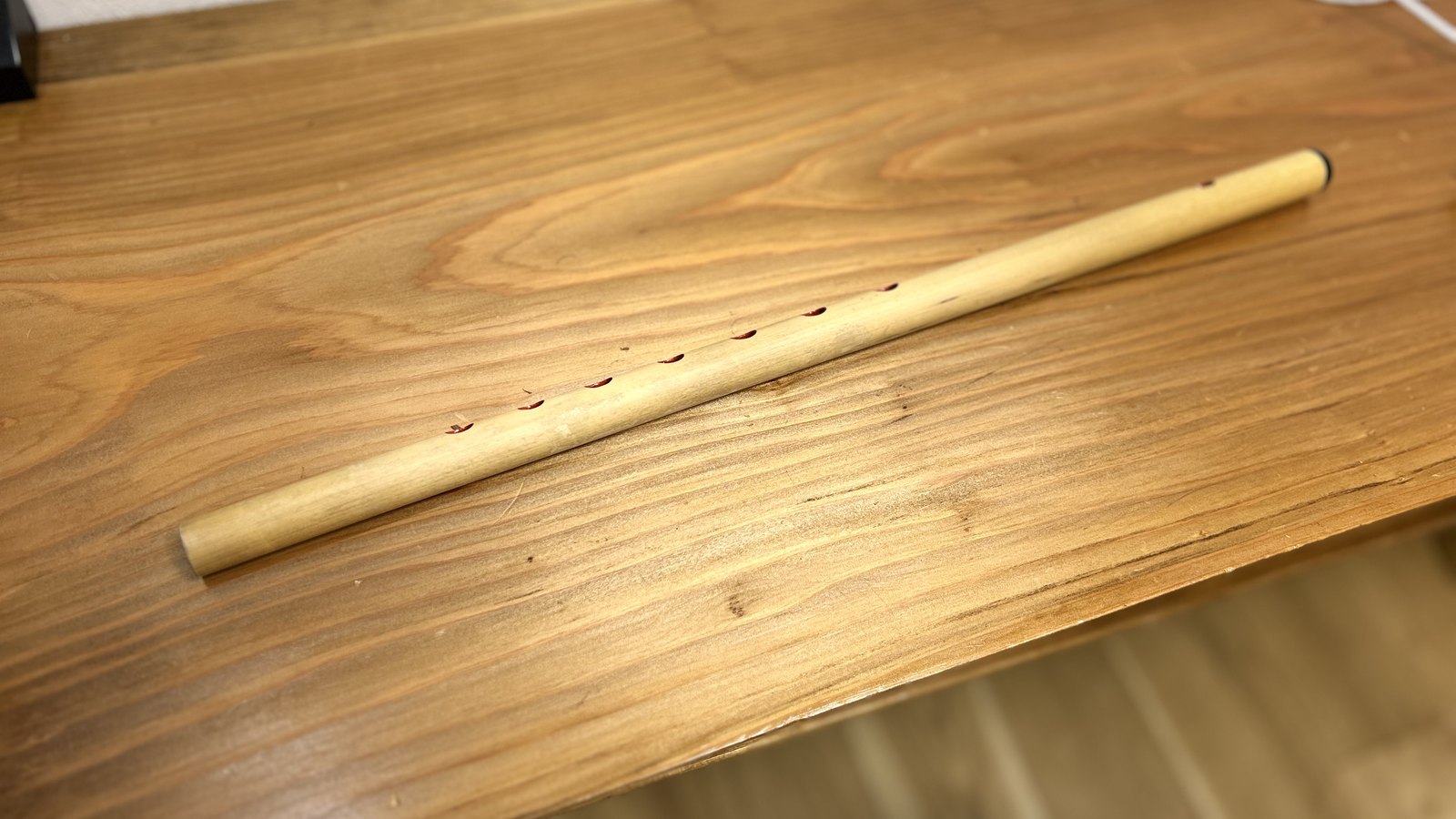 木のテーブルに置かれた、指孔の並ぶ竹の篠笛